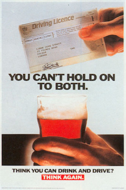A poster showing two hands, one holding an old-style British paper driving licence and the other holding a glass of beer, with the words "You can't hold on to both" in between. At the bottom is the slogan "Think you can drink and drive? Think again."