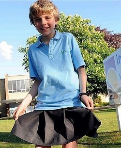 Picture of Chris Whitehead, a boy wearing a skirt, next to his school sign