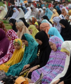 Image of Muslim women in various colour headscarves kneeling in prayer