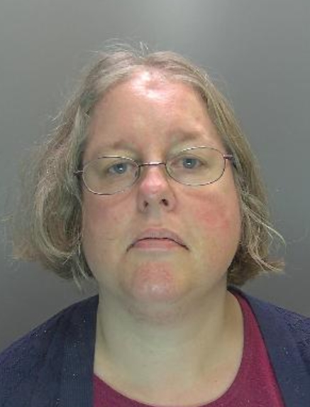 Picture of Auriol Grey, a white woman in her late 40s. She is wearing glasses, a maroon top with a dark blue jacket or coat over it.