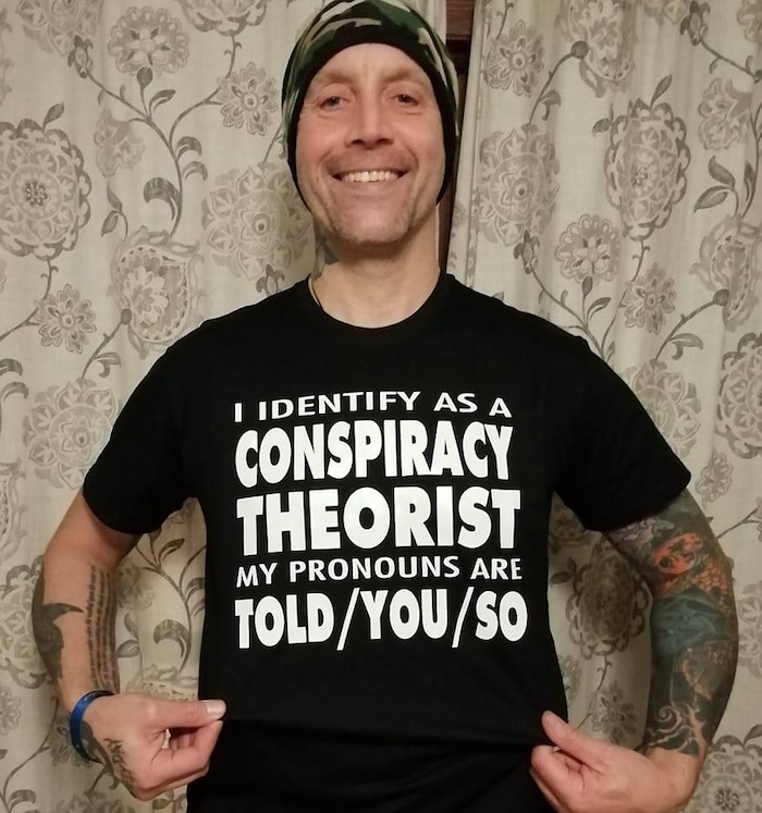 Picture of Matt Single, a white man wearing a black T-shirt which reads, in white text, "I identify as a conspiracy theorist; my pronouns are told/you/so".
