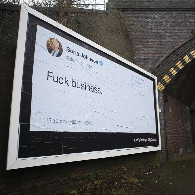 A billboard next to a brick railway bridge, presented as a tweet by Boris Johnson, with the quote "fuck business".
