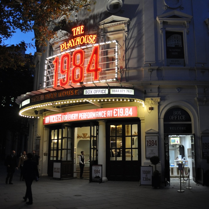 The entrance to the Playhouse theatre in London. The lit signs above the entrance says "The Playhouse: 1984".